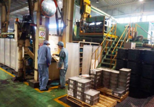 写真：工場の中で男性社員1名と男子生徒1名が作業をしている